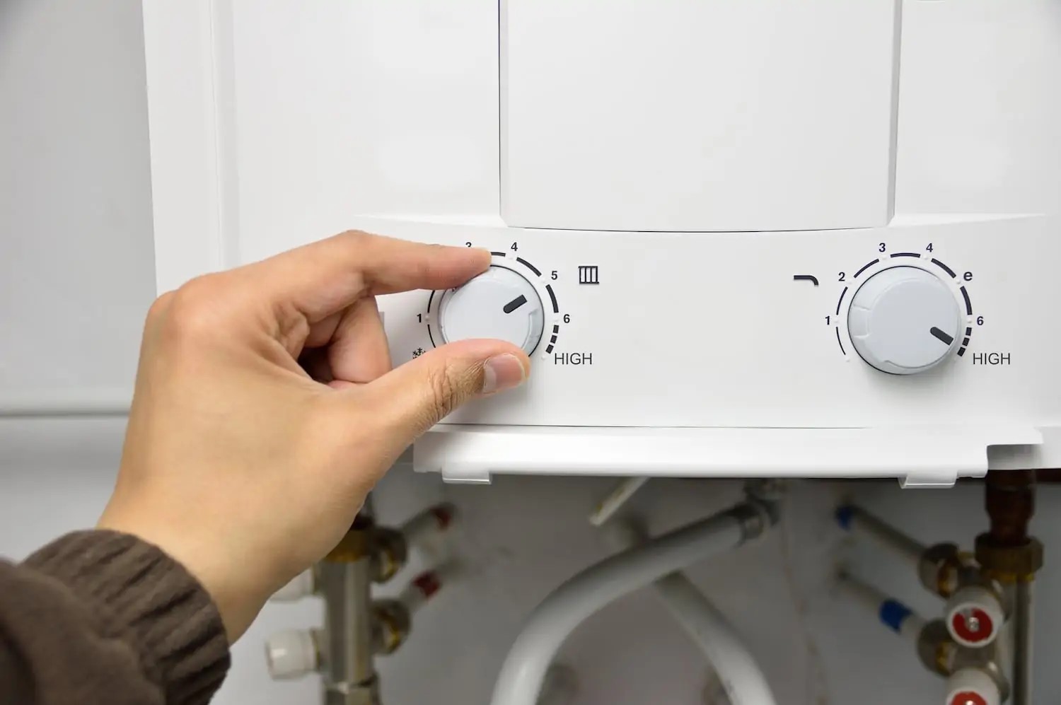 Person turning dial to adjust water heater temperature setting easily