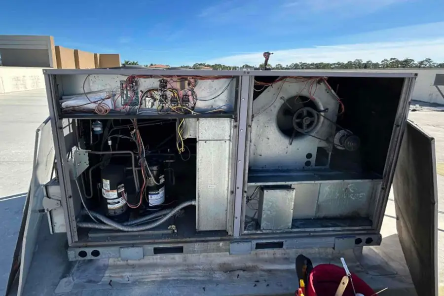 Inspecting open commercial HVAC unit on rooftop in Naples FL