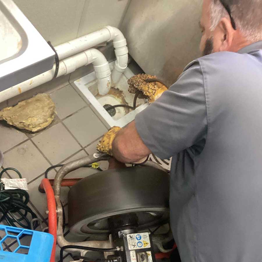 Technician performing drain cleaning with auger in Naples FL