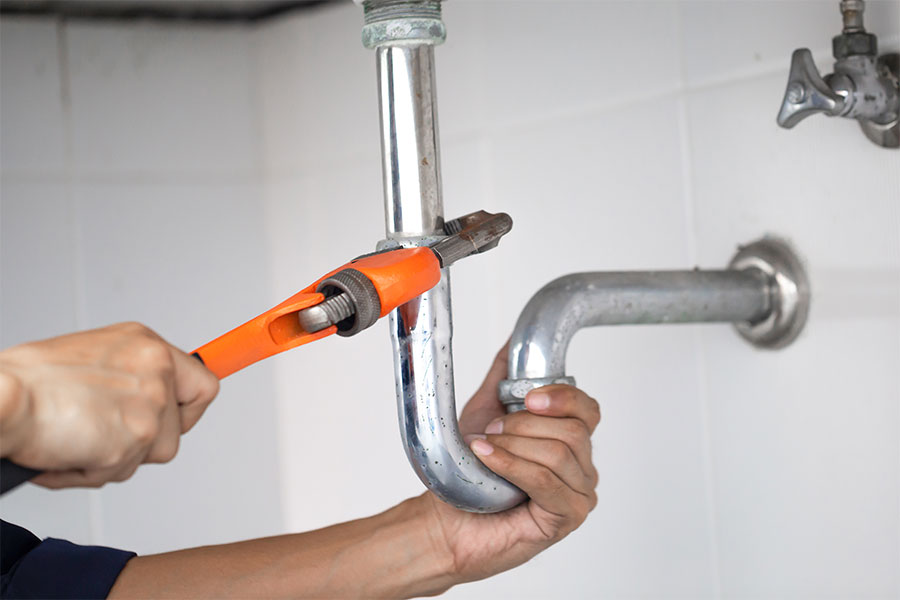 Plumber tightening pipe during plumbing inspection in Naples FL