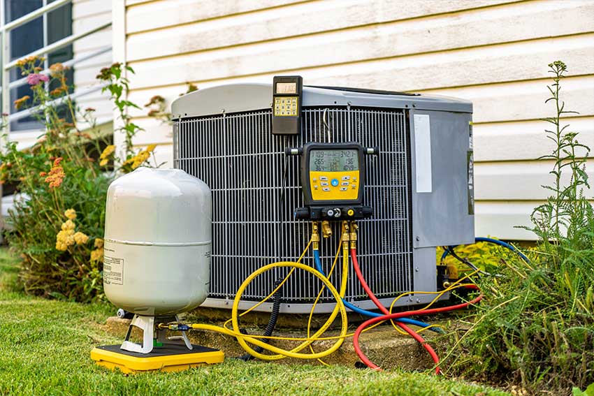 Residential AC repair showing refrigerant hoses and service equipment beside the unit