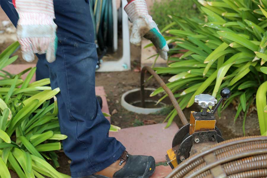 Plumber using rooter equipment to clear an outdoor drain line in Lely Resort FL