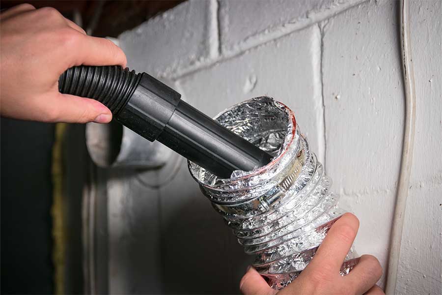 Home dryer vent cleaning with vacuum attachment clearing debris from ductwork