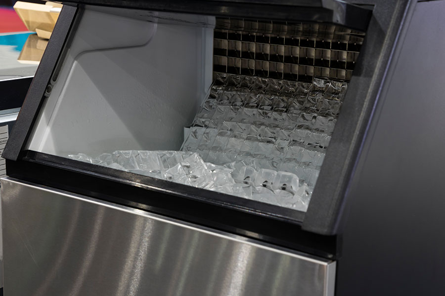 Interior view of a commercial ice machine producing cube ice for repair