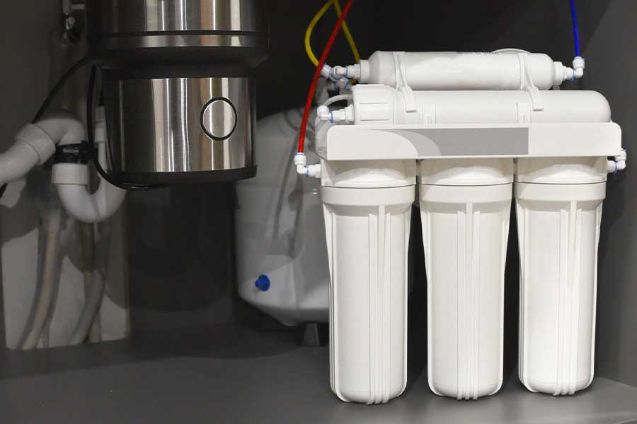 Under-sink water filtration system installed beside a garbage disposal