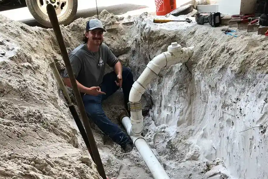 Plumber working in an excavated area during drain pipe repair service