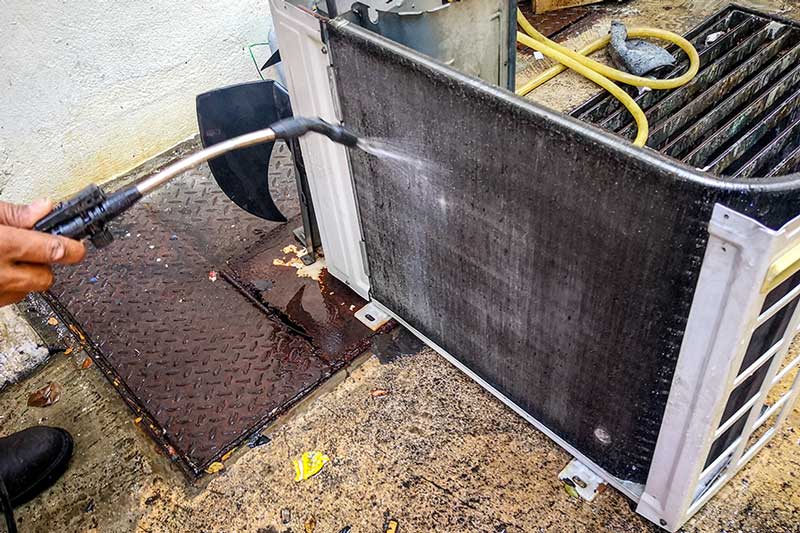 Technician cleaning a commercial HVAC coil in Naples, FL